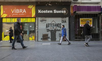 Personas caminan frente a locales comerciales cerrados de forma definitiva en la calle Florida, en la ciudad de Buenos Aires. Foto: La Jornada.