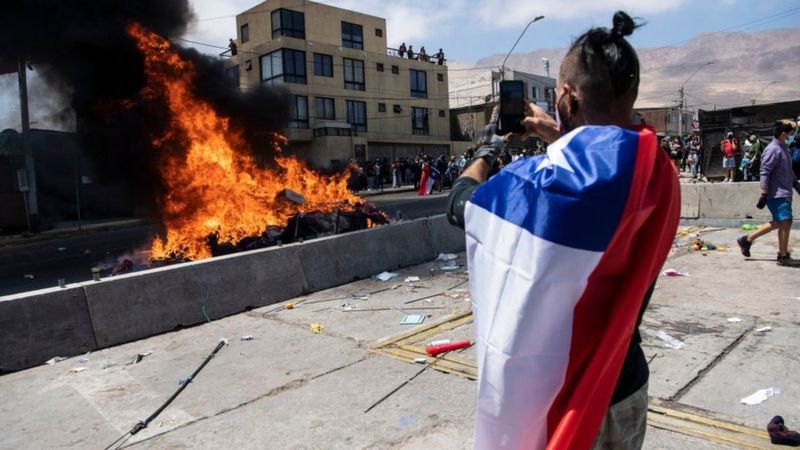 Un ciudadano toma una imagen de la quema de ropa y pertenencias de los migrantes que han llegado a Iquique en los últimos meses. Foto: Getty.