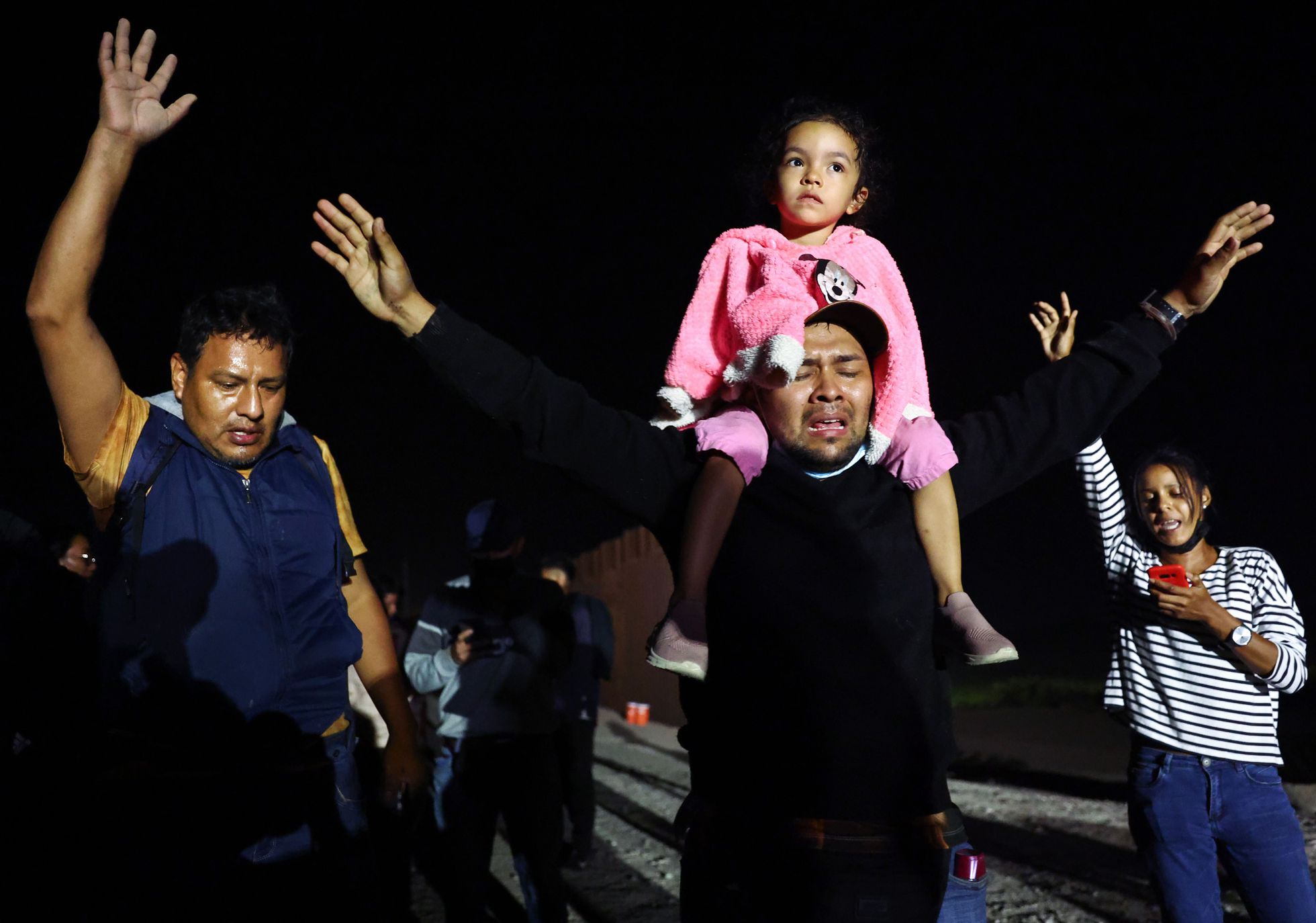 Un grupo de migrantes poco después de cruzar un hueco en la barrera fronteriza entre Estados Unidos y México, mientras esperan que la Patrulla Fronteriza los procese, el 23 de mayo de 2022 en Yuma, Arizona. Foto: El País.