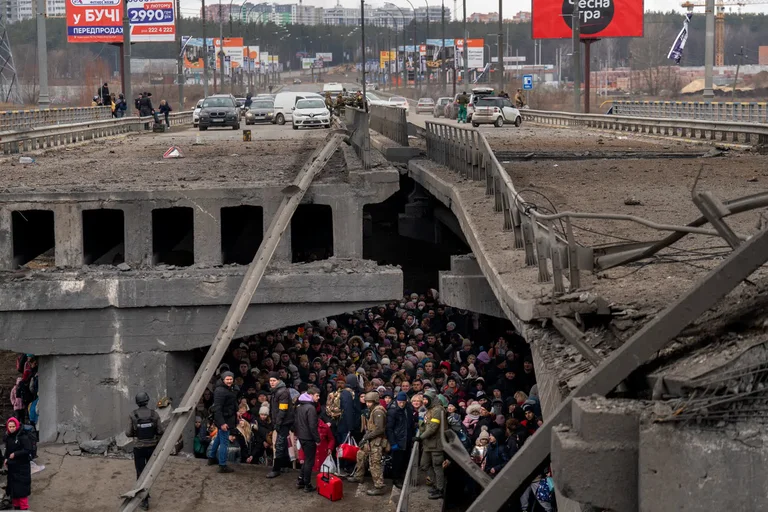 Cientos de personas que escapan de la guerra en Kyiv refugiadas bajo un puente destruido sobre el río Irpin en una imagen del 5 de marzo. Foto: Infobae