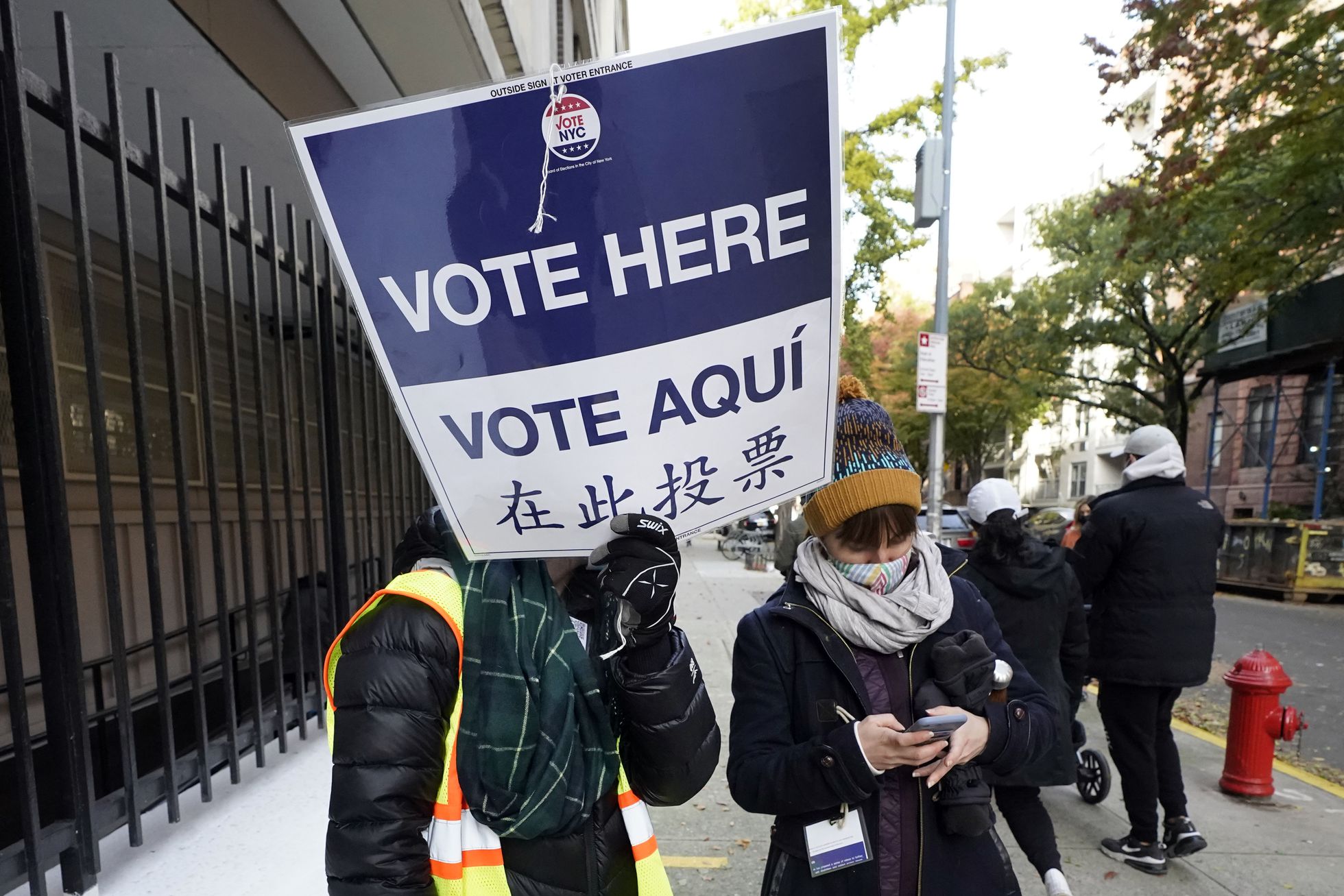 Un voluntario con un cartel escrito en inglés, español y chino, en noviembre en las elecciones locales de Nueva York. Foto: El País