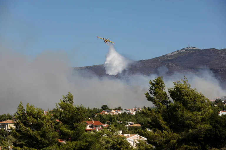 Un avión Canadair lanza agua mientras arde un incendio forestal en el suburbio de Pikermi en Atenas, Grecia. Foto: Infobae