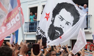 El candidato presidencial Lula junto a una enorme bandera con su imagen de una ficha policial de los ochenta, este domingo en un mitin en Río de Janeiro. Foto: El País