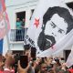 El candidato presidencial Lula junto a una enorme bandera con su imagen de una ficha policial de los ochenta, este domingo en un mitin en Río de Janeiro. Foto: El País