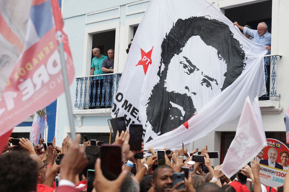 El candidato presidencial Lula junto a una enorme bandera con su imagen de una ficha policial de los ochenta, este domingo en un mitin en Río de Janeiro. Foto: El País