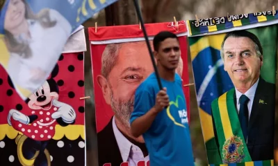 Un hombre con una bandera rodeado de toallas con las imágenes de Lula y Bolsonaro, Foto: Infobae,