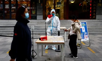 Un trabajador con traje de protección guía a las personas para que escaneen el código sanitario QR antes de someterse a la prueba de la enfermedad del coronavirus . Foto: Infobae