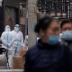 Residentes caminan cerca de los trabajadores de prevención en un complejo residencial cerrado en Beijing. Foto: Infobae