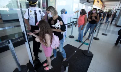 Un guardia aplica gel desinfectante a una mujer y a su hija, mientras otros ciudadanos esperan. Foto: Infobae