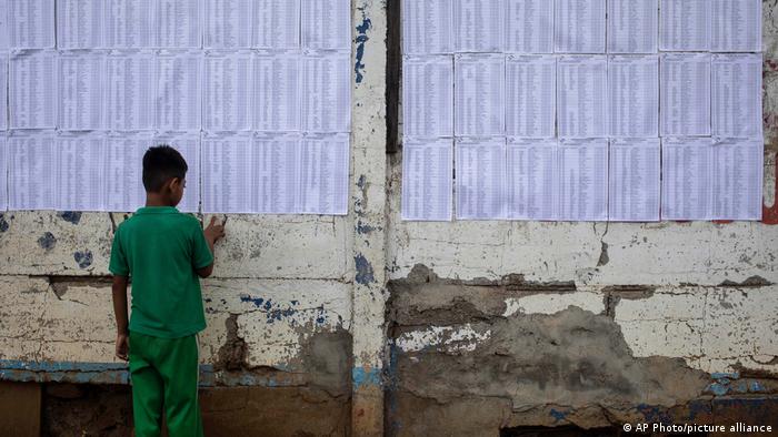 Un niño mira las listas del censo electoral pegadas en un muro ayer en Managua. Foto: DW.