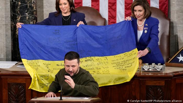 La vicepresidenta Kamala Harris y la presidenta de la Cámara de Representantes, Nancy Pelosi, a la derecha, sostienen una bandera ucraniana autografiada por las tropas de primera línea en Bakhmut, en la disputada provincia ucraniana de Donetsk, que el presidente ucraniano Volodimir Zelenski presentó a los legisladores en su visita al Capitolio en Washington. Foto: DW