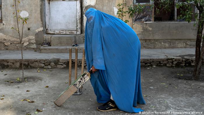 Los talibanes prohibieron a las mujeres practicar deportes. En esta foto, una mujer afgana con burka sostiene un bate de cricket. Foto: DW