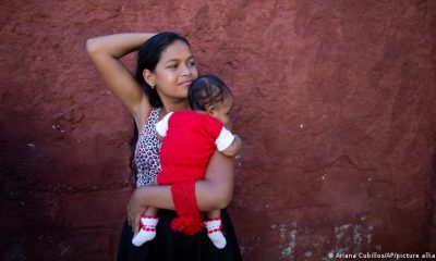 Una adolescente venezolana sostiene en brazos a su bebé en las afueras de una clínica de Caracas. Foto: DW