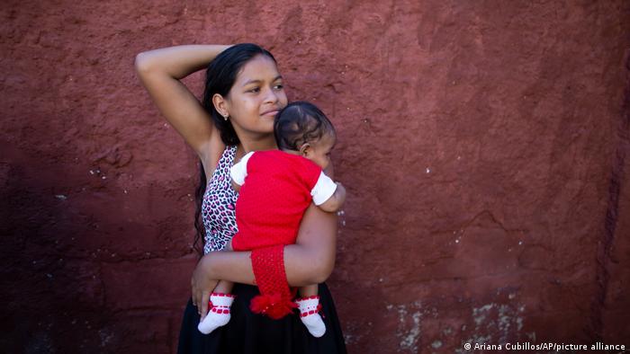 Una adolescente venezolana sostiene en brazos a su bebé en las afueras de una clínica de Caracas. Foto: DW