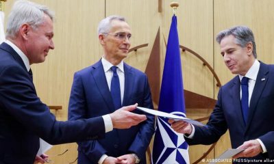 Pekka Haavisto (izq.) y Antony Blinken (der.), intercambian la documentación pertinente frente al secretario general de la OTAN, Jens Stoltenberg. Foto: DW.