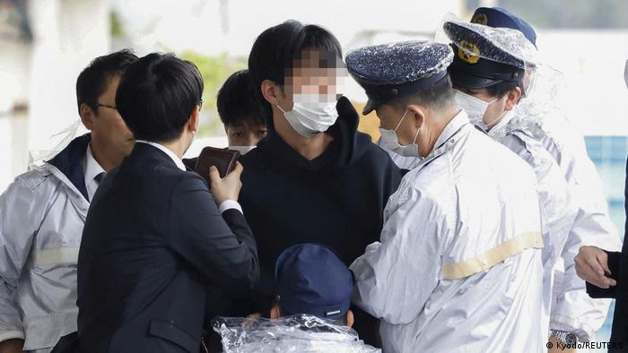 Un hombre, sospechoso de lanzar un objeto similar a una tubería cerca del primer ministro japonés, Fumio Kishida, es retenido por agentes de policía en el puerto pesquero de Saikazaki en Wakayama. Foto: DW