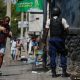 Un hombre corre con su hijo en brazos en medio de un operativo policial, en Puerto Príncipe, Haití. Foto: DW.