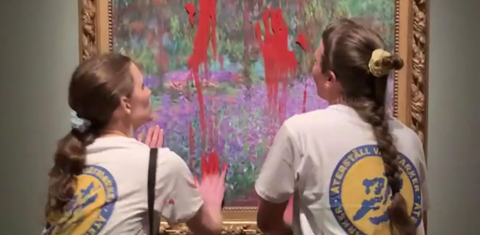 Las dos activistas detenidas en el momento de untar de pintura el cristal que protege el cuadro de Monet. Foto: La Vanguardia.