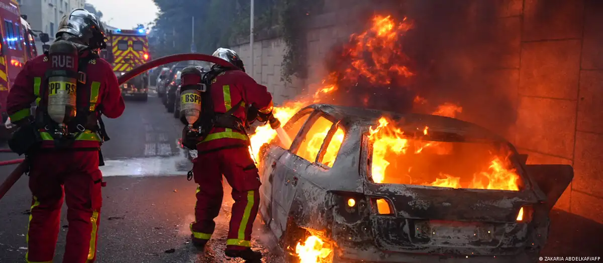 Un adolescente falleció el martes por disparos de un policía, quien disparó después de que el joven se saltase un control policial. https://p.dw.com/p/4TAp1 Durante las protestas en París también se incendiaron autos. Durante las protestas en París también se incendiaron autos.Imagen: ZAKARIA ABDELKAF/AFP PUBLICIDAD La muerte de un joven por un disparo de la policía provocó disturbios en un suburbio de París en la madrugada del miércoles (28.06.2023) y la condena de políticos y celebridades, como el futbolista Kylian Mbappé o el actor Omar Sy. El drama, que relanzó la polémica sobre la violencia policial en Francia, ocurrió el martes por la mañana en Nanterre, en la periferia oeste de París, durante un control policial al joven que conducía un auto amarillo. Un video que circuló en redes sociales, y que AFP pudo verificar, muestra como uno de los agentes retiene al conductor a punta de pistola y le dispara a quemarropa cuando este acelera con su vehículo. En la grabación se escucha "vas a recibir una bala en la cabeza", aunque no queda claro quién pronuncia estas palabras. La fuga del joven terminó unas decenas de metros más allá, cuando el coche se estrelló contra un poste. La víctima, Naël M., falleció poco después tras haber sido alcanzado en el tórax. Los hechos provocaron un estallido de disturbios en Nanterre en la noche del martes y la madrugada del miércoles, que se saldaron con 31 detenidos, 24 agentes heridos leves y unos 40 autos incendiados, según las autoridades. El ministro del Interior, Gérald Darmanin, anunció en rueda de prensa que desplegarán unos 2.000 policías y gendarmes el miércoles por la noche en los suburbios al oeste de París para evitar nuevos altercados. Foto: DW.