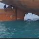 Migrantes viajaron en el timón de un barco. Foto: Captura de video.