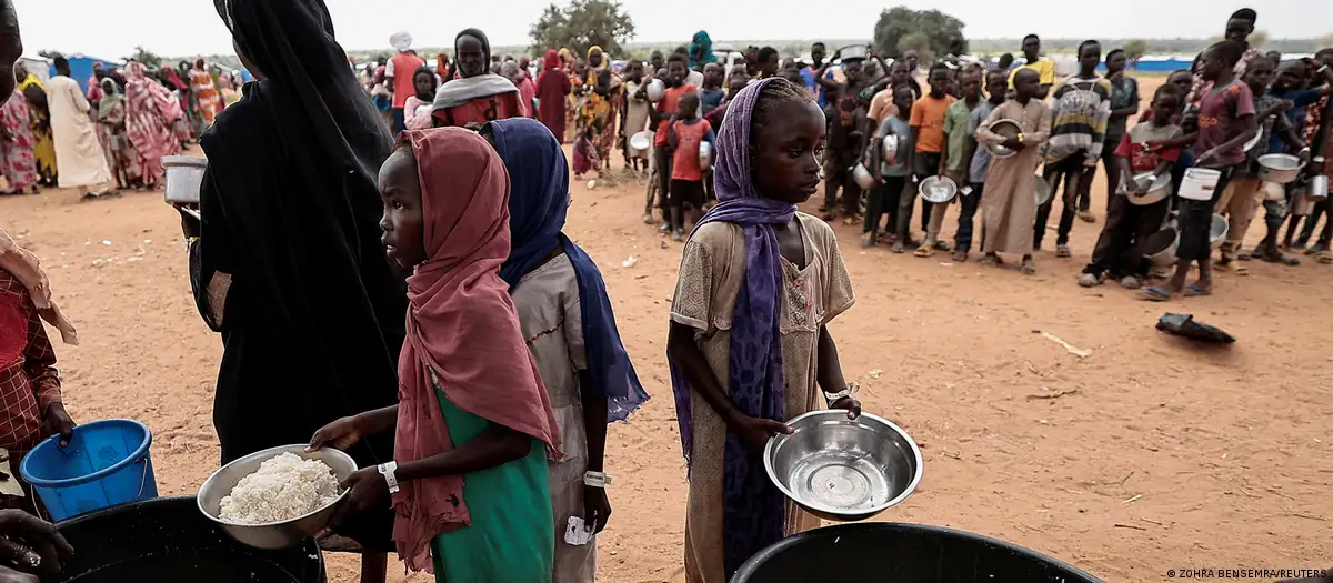 Sudaneses que huyeron del conflicto en Geneina, en la región de Darfur, reciben porciones de arroz de voluntarios de la Cruz Roja en Ourang, en las afueras de Adre, Chad. Foto: DW.