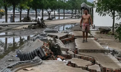 Un hombre camina sobre una calle fracturada a causa de inundaciones en Pekín. Foto:DW.