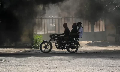 Una moto circula junto al humo de neumáticos ardiendo, durante una manifestación contra la inseguridad en Puerto Príncipe. Foto: DW.