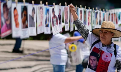 Una mujer cuelga un retrato de una persona desaparecida en un memorial improvisada a lo largo de la Avenida Reforma de Ciudad de México, en el Día Internacional de las Víctimas de Desapariciones Forzadas. Foto. DW.