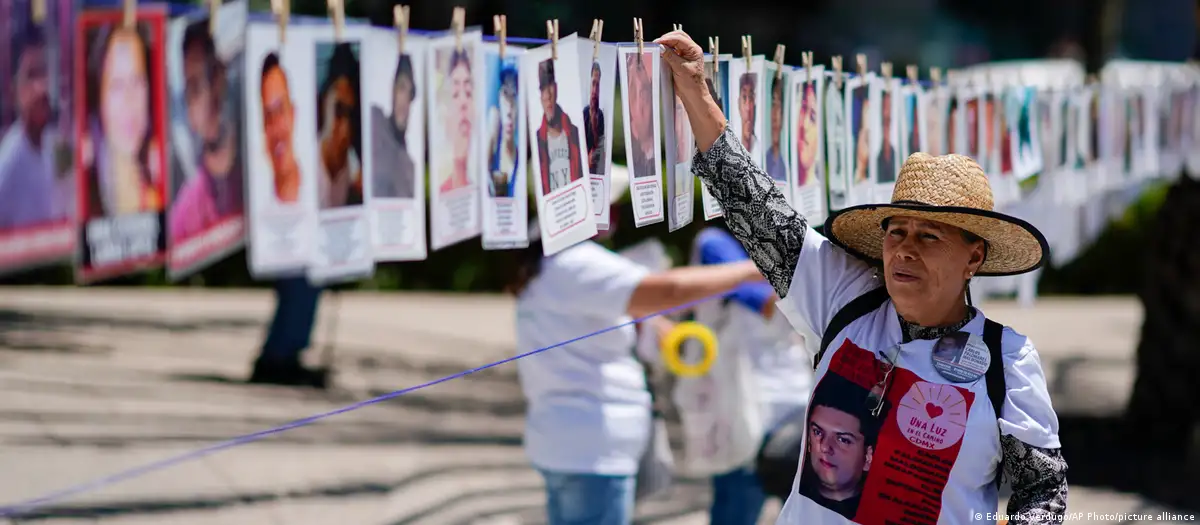 Una mujer cuelga un retrato de una persona desaparecida en un memorial improvisada a lo largo de la Avenida Reforma de Ciudad de México, en el Día Internacional de las Víctimas de Desapariciones Forzadas. Foto. DW.