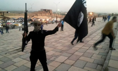 Un combatiente del Estado Islámico sostiene una bandera del ISIS . Foto: Infobae.