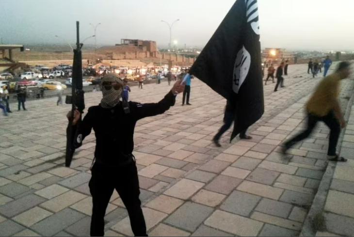 Un combatiente del Estado Islámico sostiene una bandera del ISIS . Foto: Infobae.