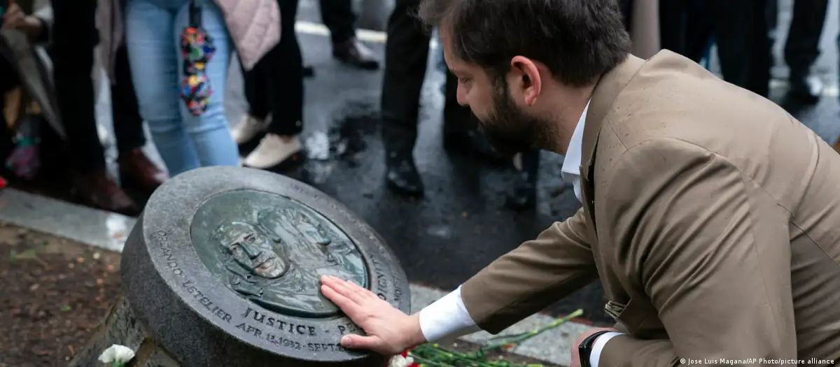 Gabriel Boric toca la placa que recuerda la memoria de Orlando Letelier y Ronni Moffitt. Foto: DW.