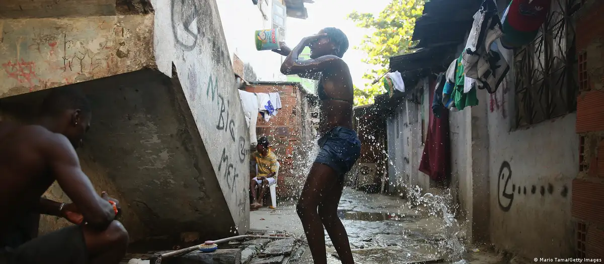 Un adolescente se baña con agua recogida de una tubería en Complexo da Mare, uno de los complejos de favelas más grandes de Río de Janeiro. Foto: DW.