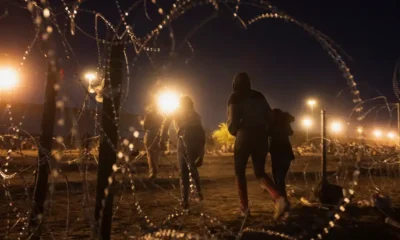 Migrantes cruzan un hueco en una valla de serpentina metálica, cerca del muro fronterizo entre México y Estados Unidos en El Paso, Texas. Fuente: DW. Archivo.