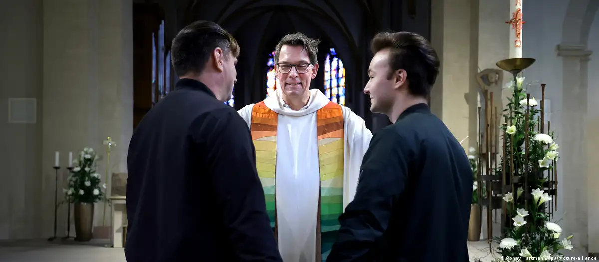 Bendición con un arcoiris: un clérigo y una pareja gay en la iglesia episcopal de Magdeburgo. Foto: DW.