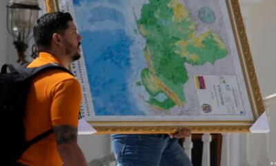 Un hombre carga un mapa del Esequibo. Foto: DW.