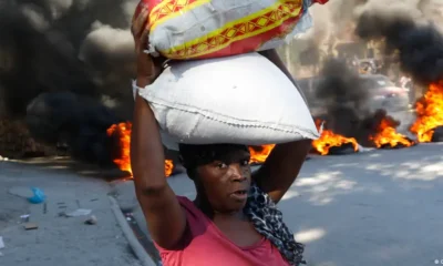 Una mujer pasa junto a neumáticos quemados por manifestantes en Puerto Príncipe, para llamar la atención sobre la inseguridad del país y exigir la renuncia del primer ministro Ariel Henry. Foto de archivo. DW.