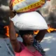 Una mujer pasa junto a neumáticos quemados por manifestantes en Puerto Príncipe, para llamar la atención sobre la inseguridad del país y exigir la renuncia del primer ministro Ariel Henry. Foto de archivo. DW.