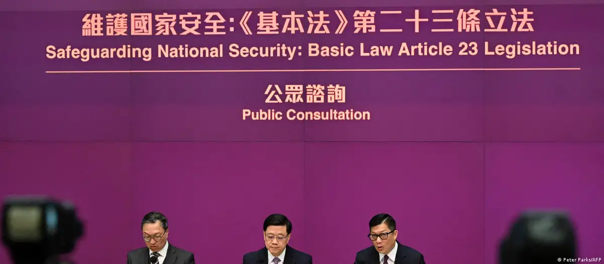 El director ejecutivo de Hong Kong, John Lee (centro), el secretario de Justicia, Paul Lam (izquierda), y el secretario de Seguridad, Chris Tang (derecha), celebran una conferencia de prensa en la sede del gobierno hongkonés. Foto: DW.