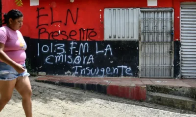 Una mujer camina frente a una pared con un lema del ELN en la región de Cúcuta, Colombia. Foto: DW.