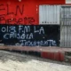 Una mujer camina frente a una pared con un lema del ELN en la región de Cúcuta, Colombia. Foto: DW.