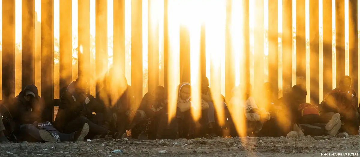 Migrantes esperan a ser transportados por la patrulla fronteriza de EE.UU. después de cruzar el muro fronterizo hacia los EE.UU. desde México. Foto: DW.