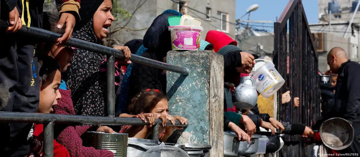 Un grupo de niños espera comida en una cocina comunitaria en Gaza. Foto; DW.