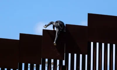 un migrante trepando por la valla fronteriza hacia Estados Unidos. Imagen: GUILLERMO ARIAS/AFP