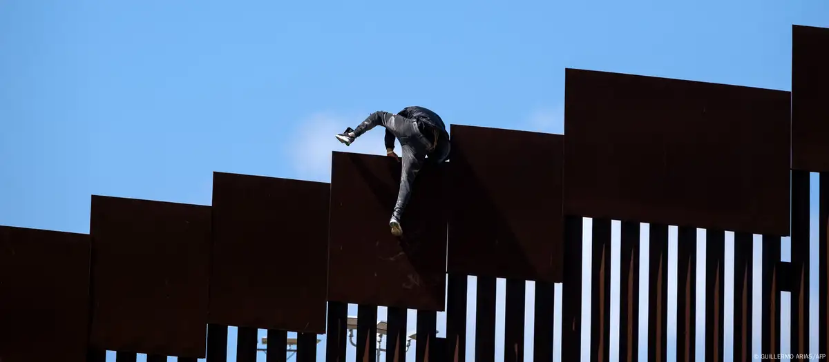 un migrante trepando por la valla fronteriza hacia Estados Unidos. Imagen: GUILLERMO ARIAS/AFP