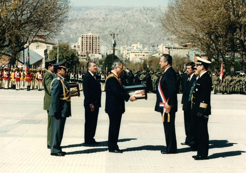 El presidente Gonzalo Sánchez de Losada entrega al presidente Juan Carlos Wasmosy las banderas paraguayas tomadas en la batalla de Cañada Strongest, durante la ceremonia de devolución de los trofeos de guerra. La Paz, agosto de 1994. Cortesía