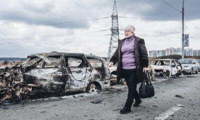 Una mujer camina delante de unos coches quemados en un puente de Irpin, a 7 de marzo de 2022, en Irpin (Ucrania). Foto: Europa Press.