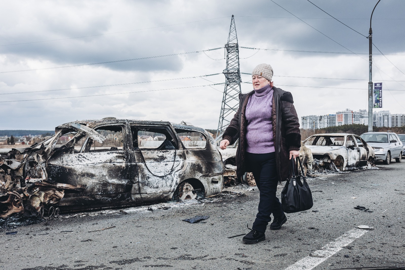 Una mujer camina delante de unos coches quemados en un puente de Irpin, a 7 de marzo de 2022, en Irpin (Ucrania). Foto: Europa Press.