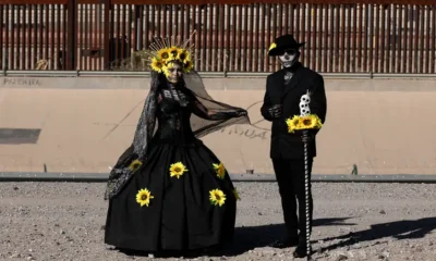 Una pareja de migrantes mexicanos que buscan asilo en Estados Unidos, vestidos como Catrina y Catrín, junto a la frontera. Foto:D W