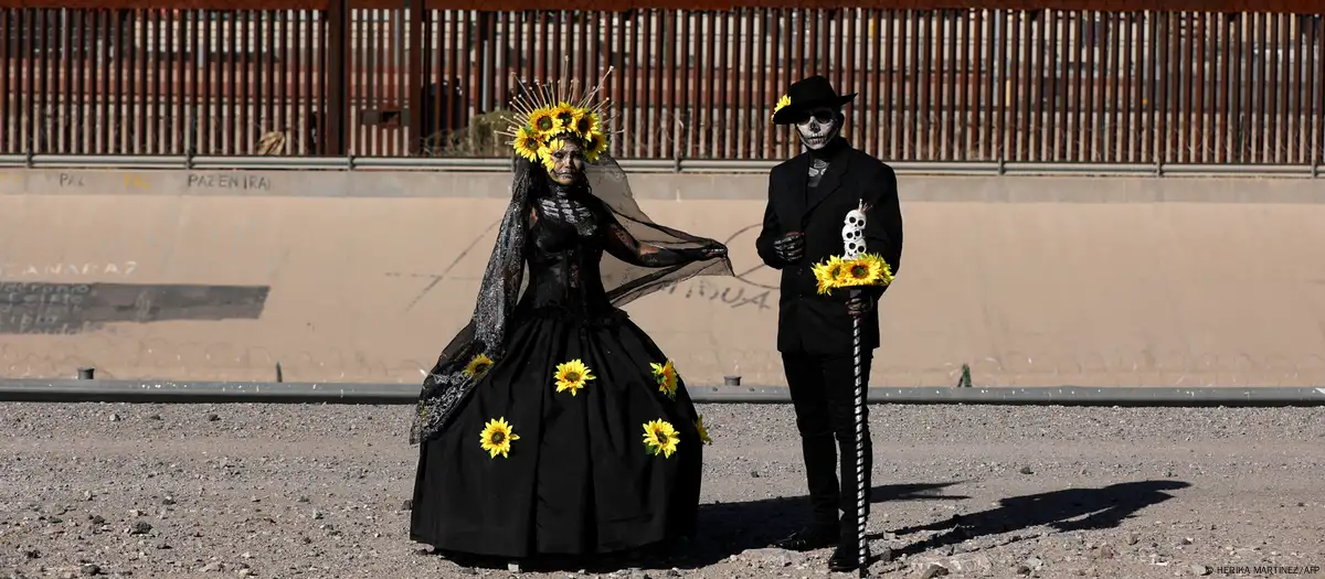 Una pareja de migrantes mexicanos que buscan asilo en Estados Unidos, vestidos como Catrina y Catrín, junto a la frontera. Foto:D W